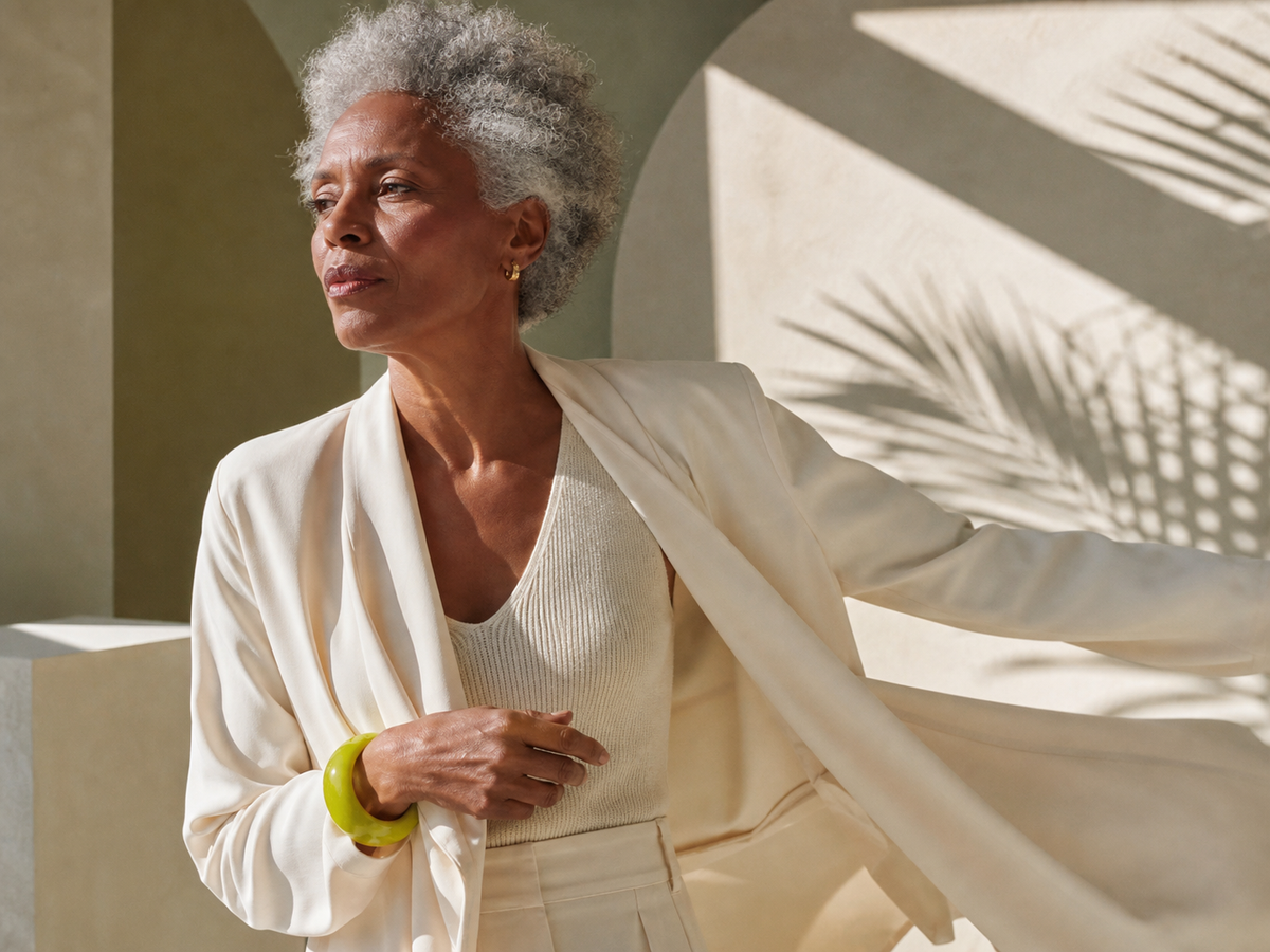 Older woman in cream tailoring photographed in warm geometric light
