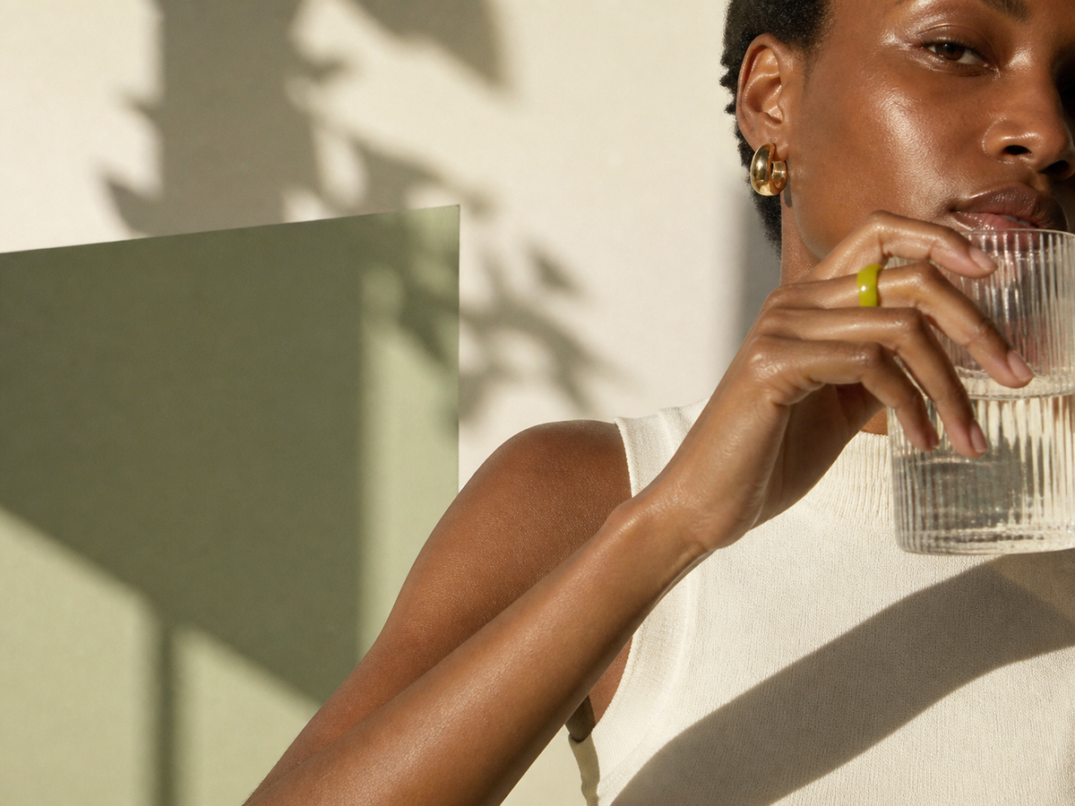Fashion editorial portrait with a glass of water in cream and sage light