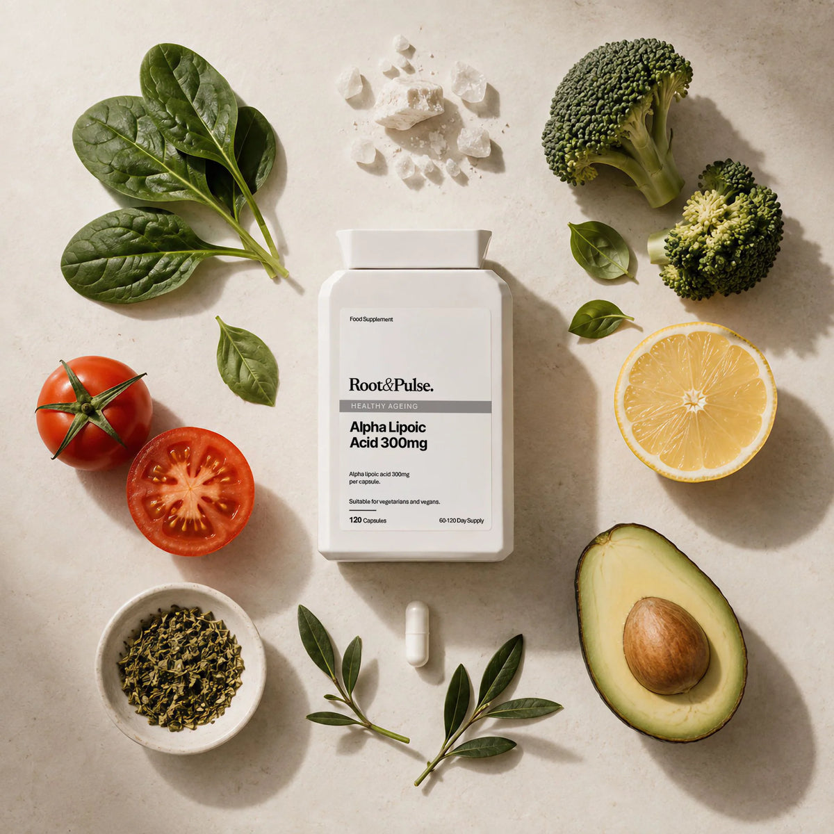 A white supplement bottle labeled Root & Pulse Alpha Lipolic Acid 300mg, arranged in a flat lay on a light beige surface with spinach, broccoli, tomatoes, lemon, avocado, and green herbs around it.