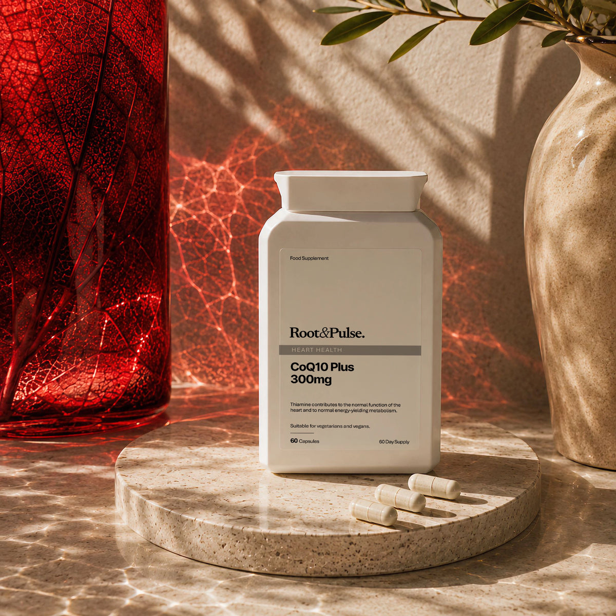A white supplement bottle labeled Root of Pulse CoQ10 Plus 300mg stands on a round stone pedestal with a few capsules beside it. The scene is styled with warm sunlight, shadows, a red glass vase, and a beige ceramic vase.