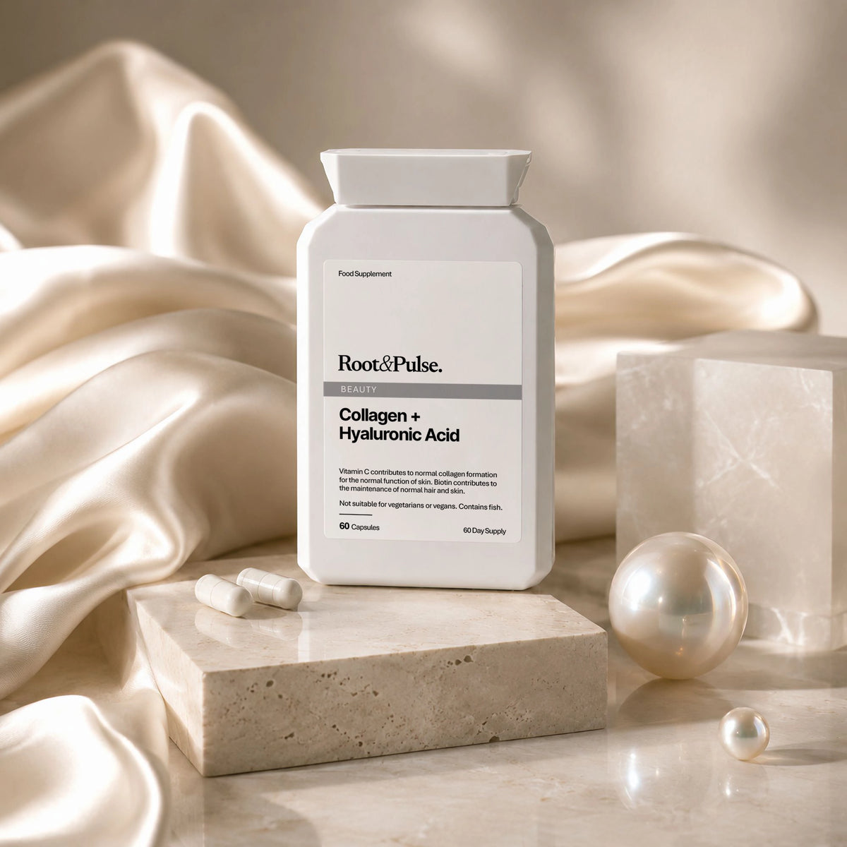 A white supplement bottle labeled Root of Pulse Collagen + Hyaluronic Acid, styled on a marble block with pearls and draped satin fabric in warm beige tones.