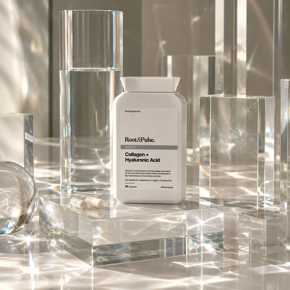 A white bottle of Root&Pulse Collagen + Hyaluronic Acid capsules sits on a reflective surface surrounded by clear acrylic blocks and glassware, with dramatic light reflections and shadows.