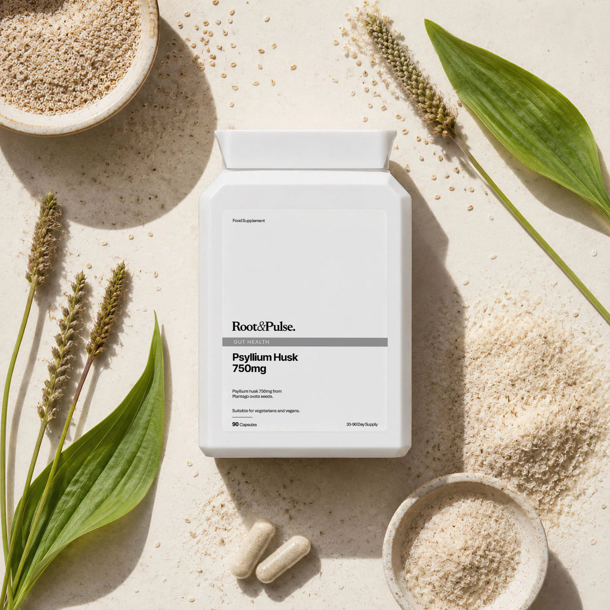 A white bottle of Root & Pulse Psyllium Husk 750mg centered on a light beige textured surface, surrounded by loose psyllium powder, whole grains, and green leaves in a styled flat-lay composition.