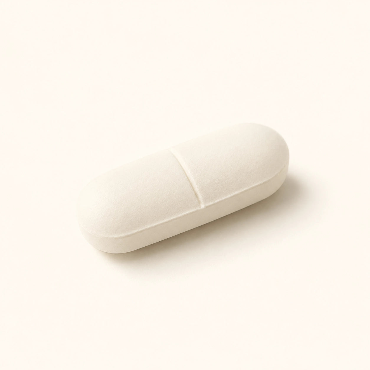 A single off-white capsule-shaped pill or cushion-like product photographed on a clean warm cream background.